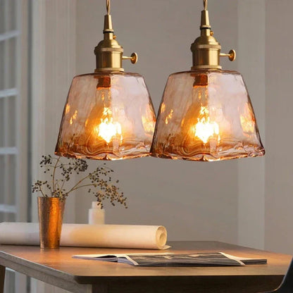 Pair of amber marbled Aurelia glass pendants above a console table