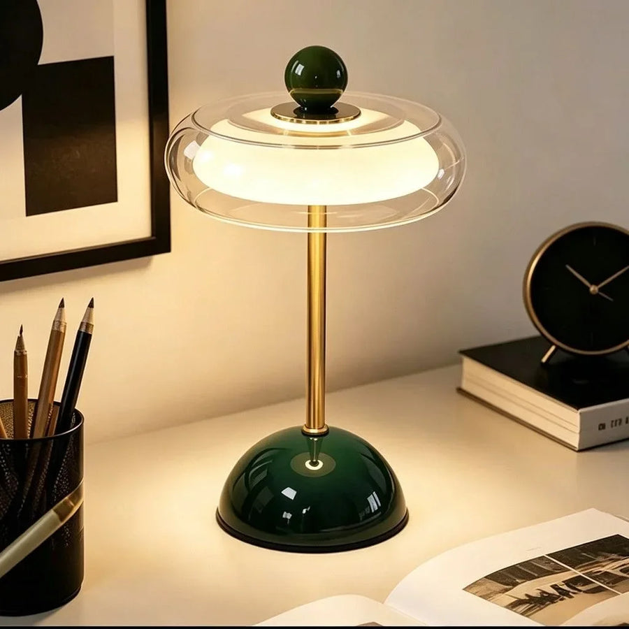 Green Sorrel glass lamp glowing beside pencils and a clock