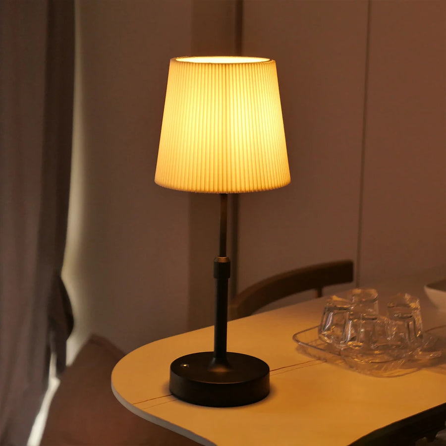 Black Nella cordless fabric lamp glowing on a side table
