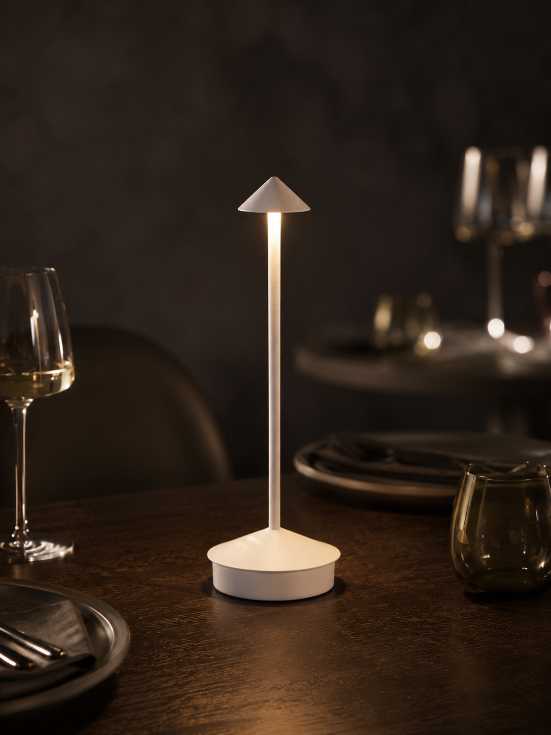 Ember Aura cordless lamp glowing on a dark oak dining table