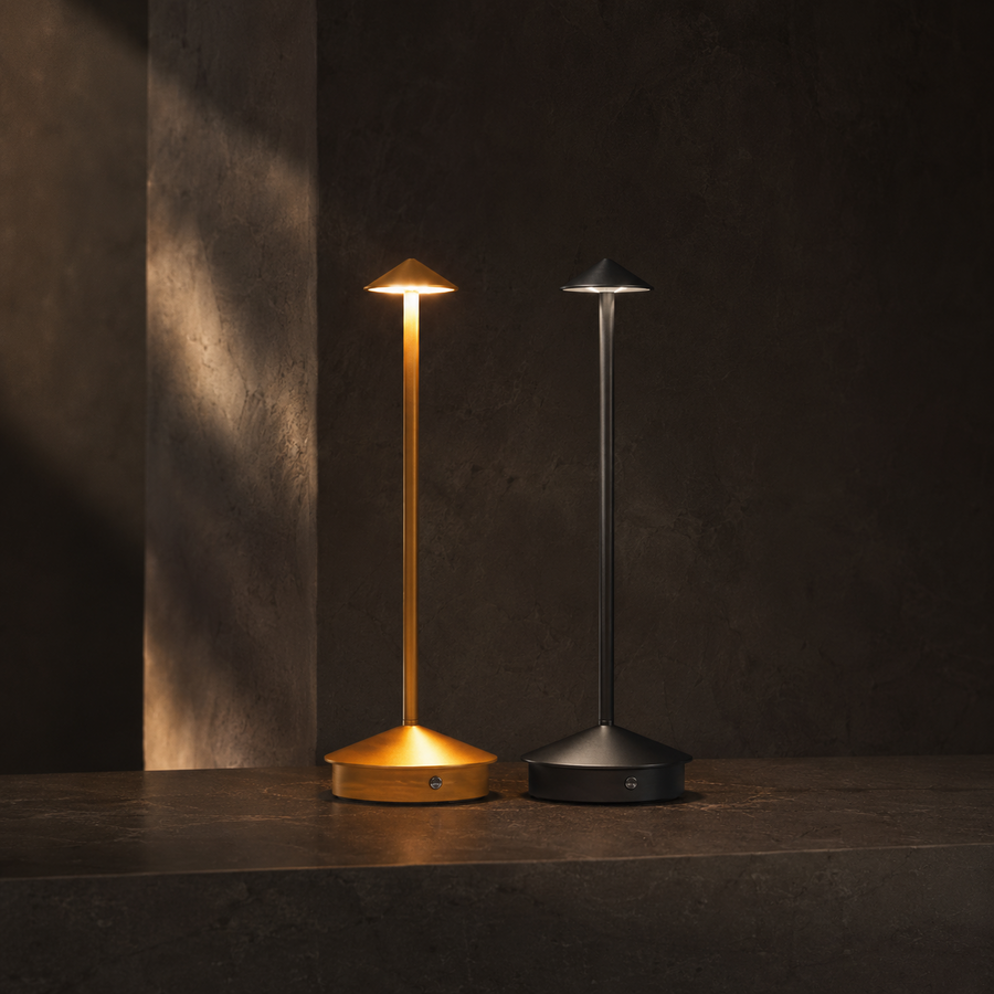 Ember Garden cordless outdoor lamps in gold and black on dark stone at dusk