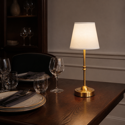 Gold Laurent table lamp glowing on a dark dining table