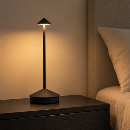 Black Sera cordless lamp glowing on a bedroom nightstand