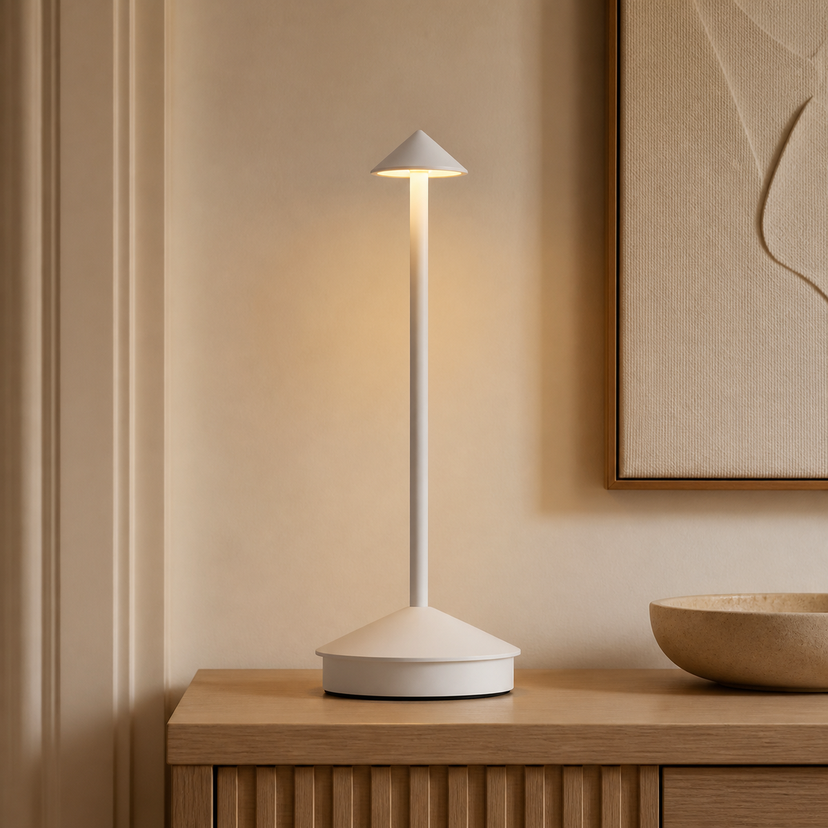 White Sera cordless lamp on a wood console below framed art