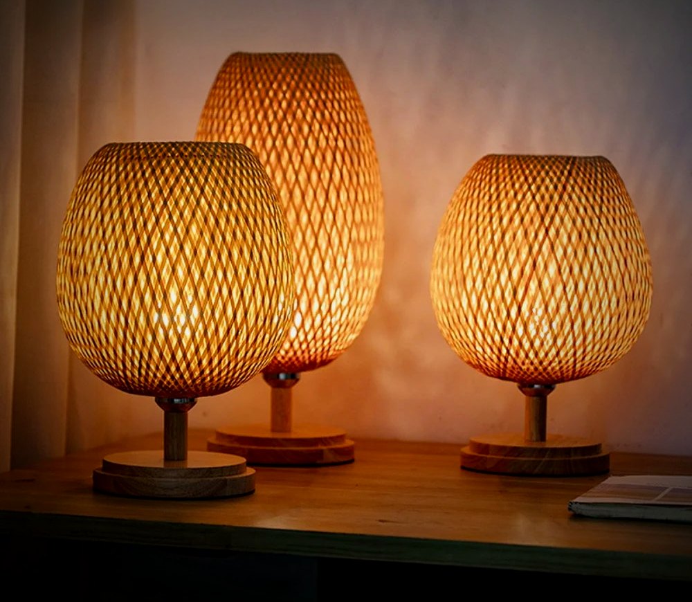 Willow hand-woven bamboo table lamps, Tall and Wide, glowing on a wood console